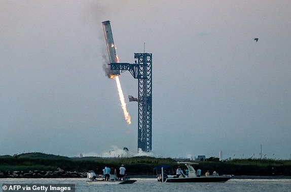 TOPSHOT - Starship's Super Heavy Booster is grappled at the launch pad in Starbase near Boca Chica, Texas, on October 13, 2024, during the Starship Flight 5 test. SpaceX successfully "caught" the first-stage booster of its Starship megarocket Sunday as it returned to the launch pad after a test flight, a world first in the company's quest for rapid reusability. (Photo by SERGIO FLORES / AFP) (Photo by SERGIO FLORES/AFP via Getty Images) *** BESTPIX ***